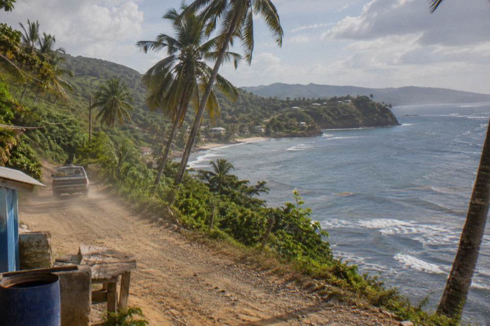 Coastal road winding between green palm covered hills above a calm blue bay