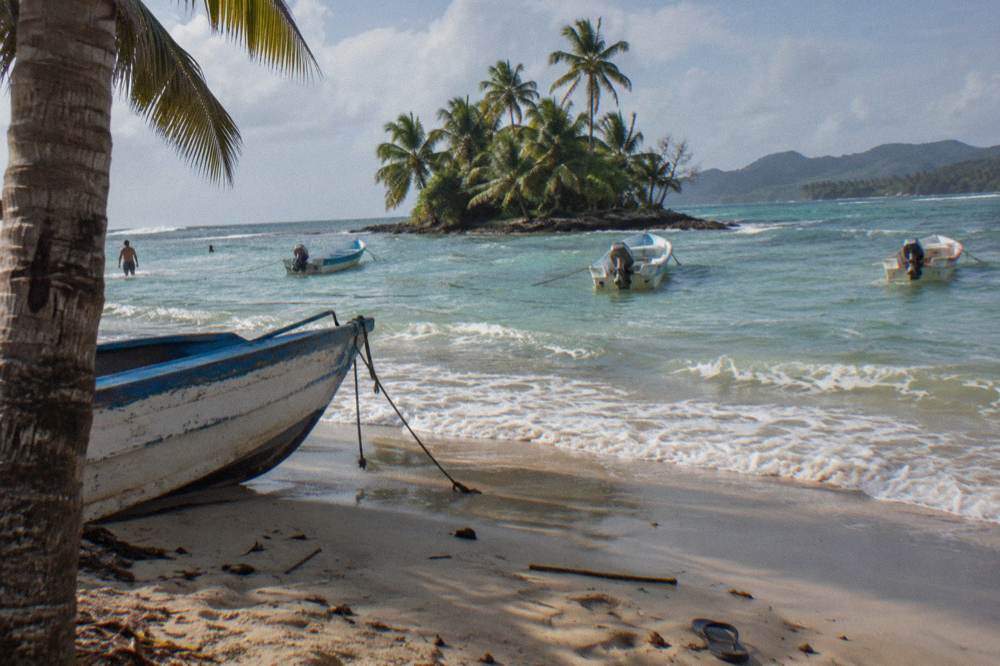 Turquoise shallows around a small island with palm trees and moored boats