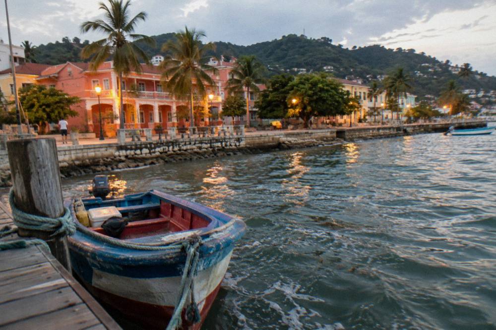 Wooden boat moored at a dock in Samaná town with the malecon waterfront in the background