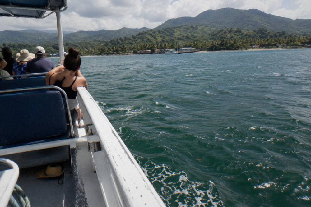 A whale watching boat with passengers along the rail on open water in Samaná Bay.