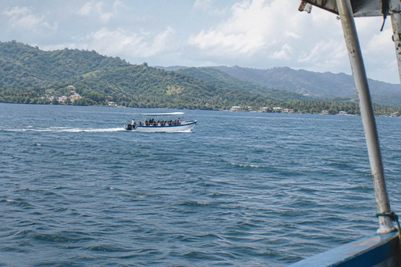 A whale watching boat crossing the calm blue water of Samaná Bay under a morning sky