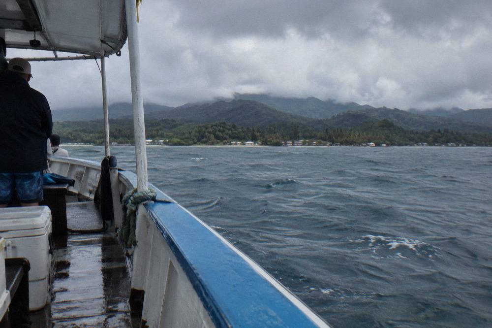A whale-watching boat on calm water near the forested coast of Samaná Bay