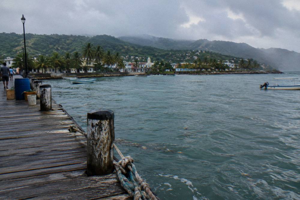 Wooden pier extending into calm green water near Samana at morning