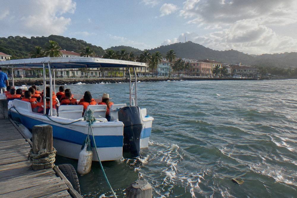 A tour boat with passengers along the waterfront of Samana town on a clear morning