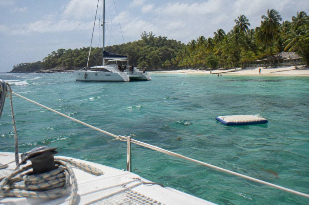 A catamaran moored near the white sand beach of Cayo Levantado with turquoise water