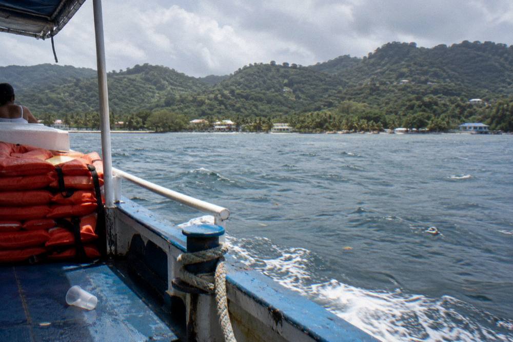 A small boat with life jackets on board drifting near forested coastline in Samana Bay
