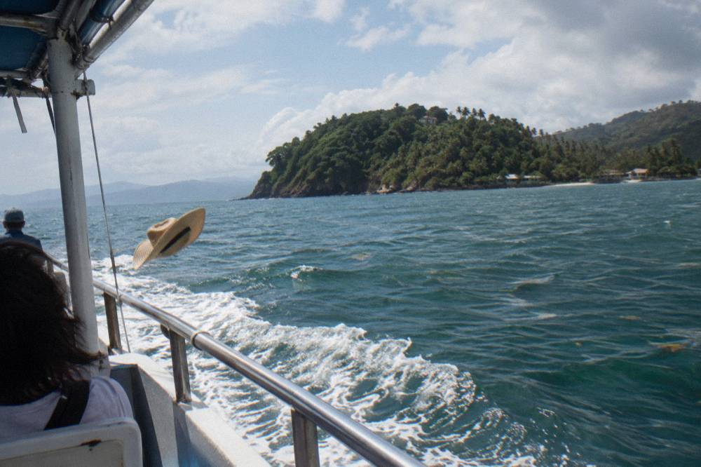 Tour boat cruising across calm blue-green water toward a forested island
