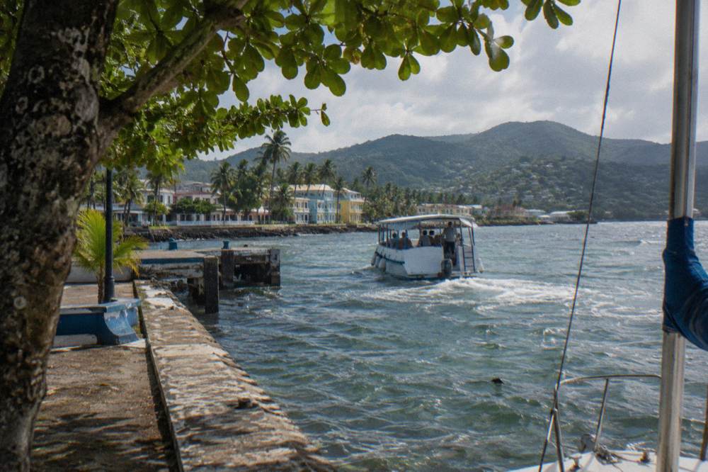 A small tour boat leaving a Caribbean waterfront dock in morning light