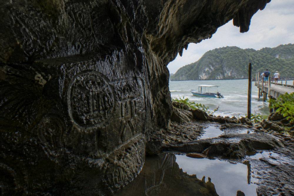 Ancient Taíno petroglyphs carved into the dark rock wall inside a sea cave