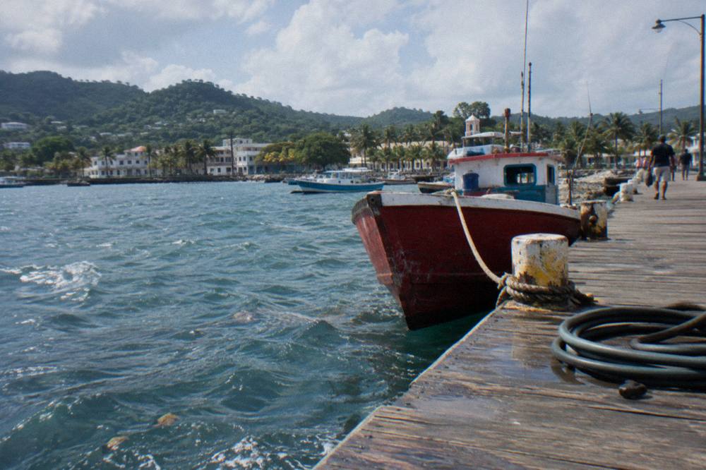 A wooden pier on the Samaná waterfront with small boats moored in calm morning water