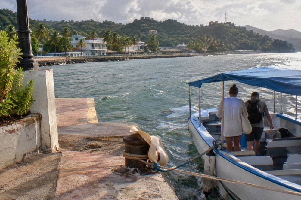 Passengers boarding a small excursion boat at a wooden dock in early morning light