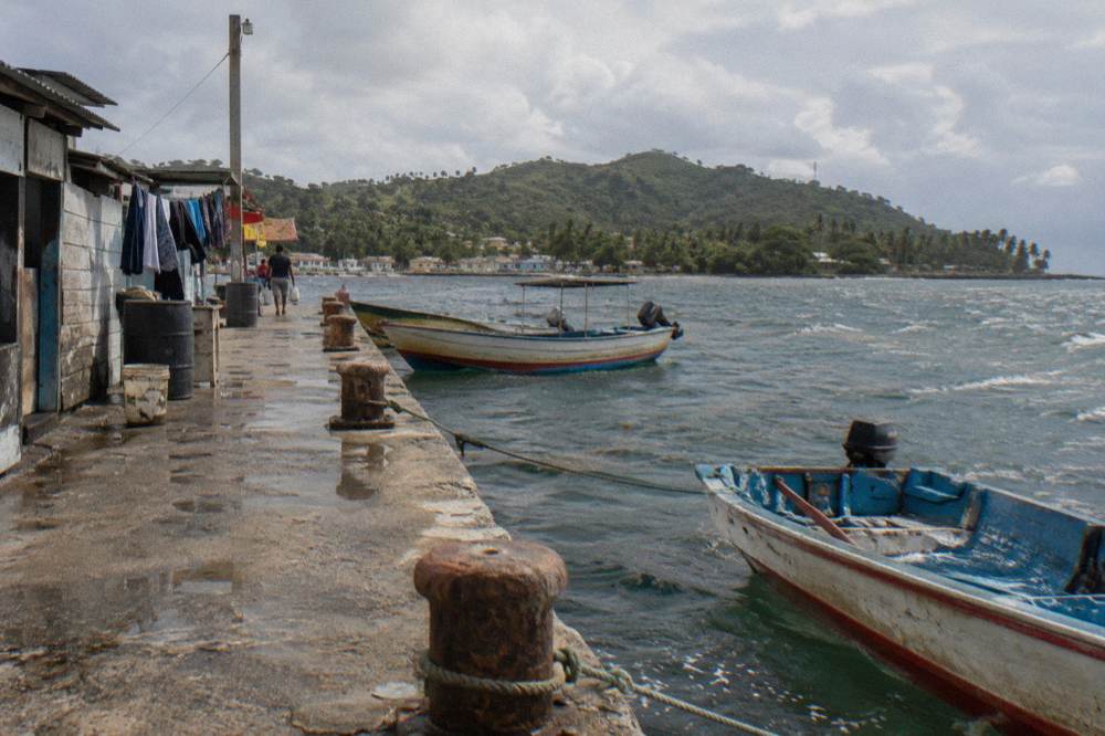 A wooden observation boat moored at a town dock with calm water and hills behind