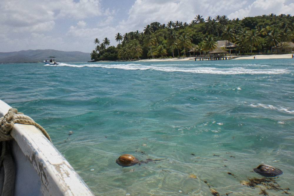 Turquoise shallow water near a small palm covered island with a boat wake crossing the bay