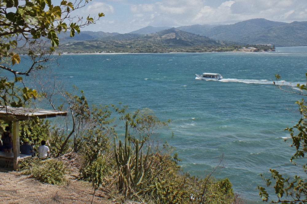 Whale watching boat crossing Samaná Bay under a clear morning sky