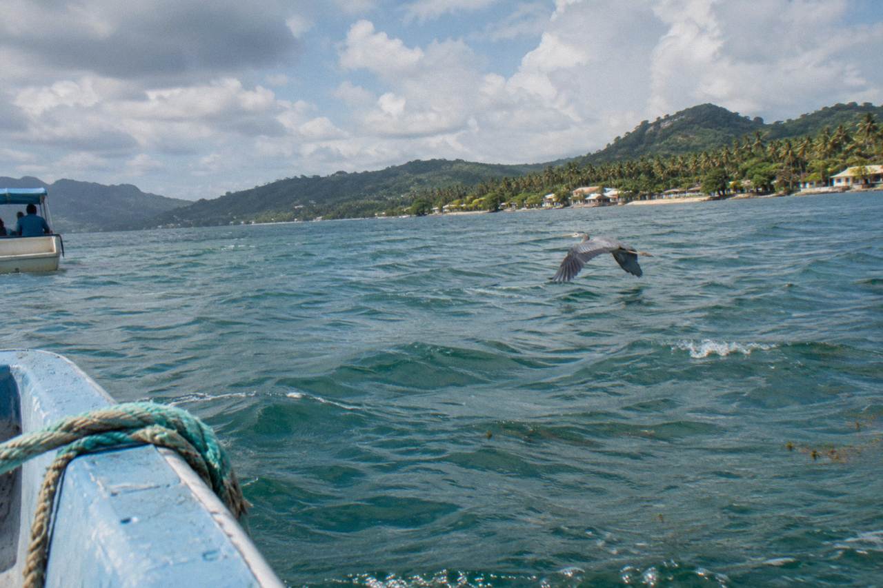 Calm turquoise water of Samana Bay under a partly cloudy morning sky
