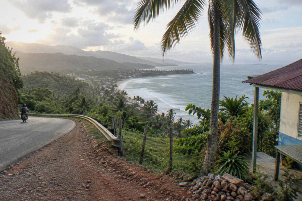 A coastal road curving along green hills above the sea.