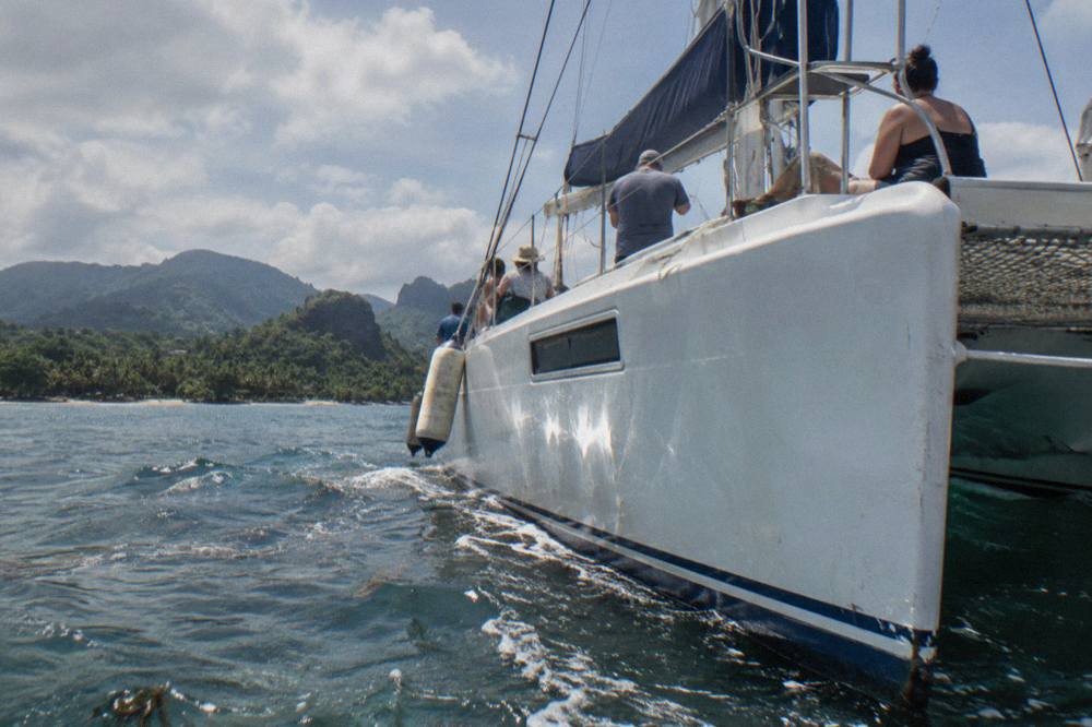 A covered whale watching boat with rows of seats crossing the open water of Samaná Bay