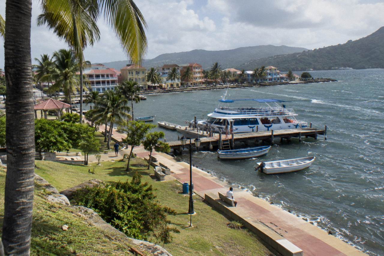 A whale watching boat moored at a wooden dock on the Samaná waterfront on a calm morning