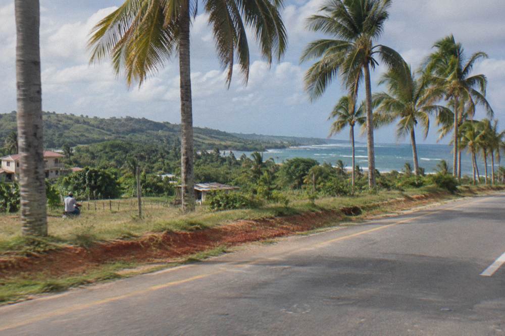 A tour bus on a highway through green Dominican countryside in morning light