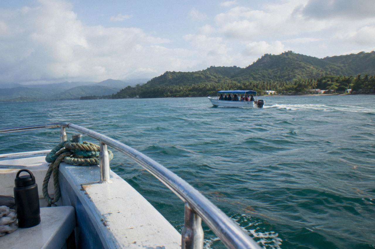 A whale watching boat crossing the calm open water of Samana Bay under a wide morning sky