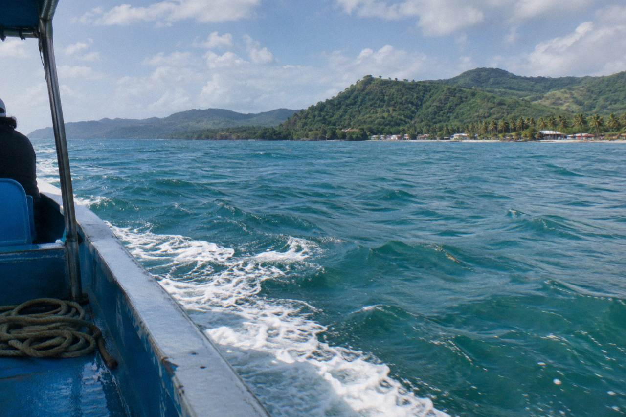 Whale watching boat on calm turquoise water in Samana Bay with green hills behind