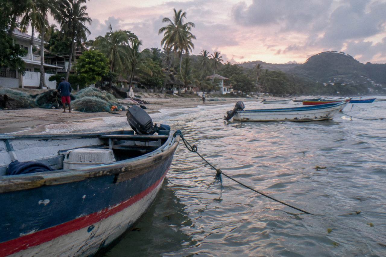 Wooden fishing boats moored beside a calm Caribbean bay in the early morning