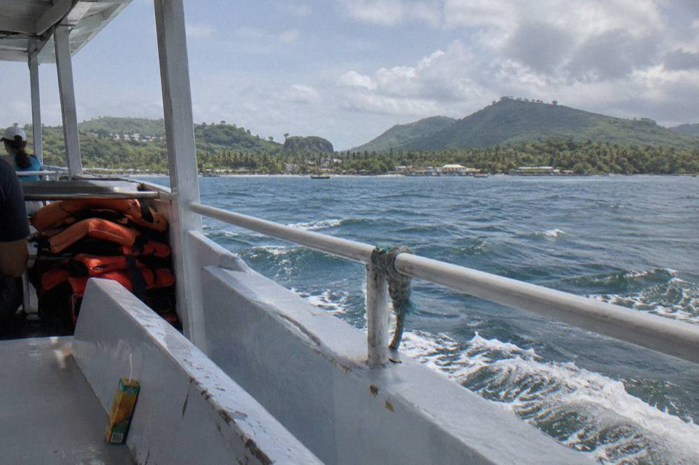 A covered whale watching boat cruising on calm blue water in Samaná Bay