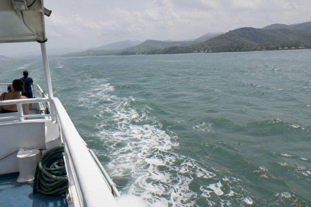 A boat crossing open water in Samana Bay with hills on the horizon