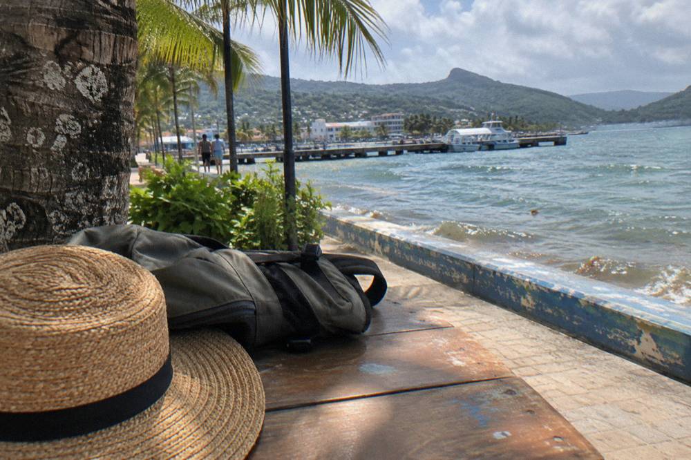 A wooden day pack and sun hat set out on a bench beside a water bottle