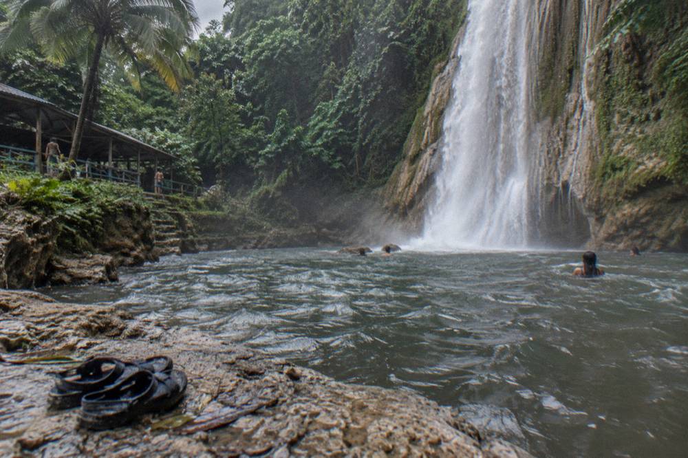 A forest trail with a waterfall dropping into a rocky pool