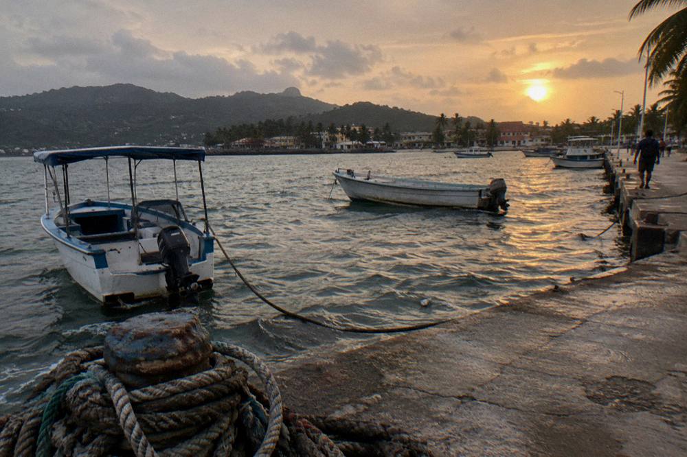 Evening light over Samaná Bay with the coastline and moored boats in the distance